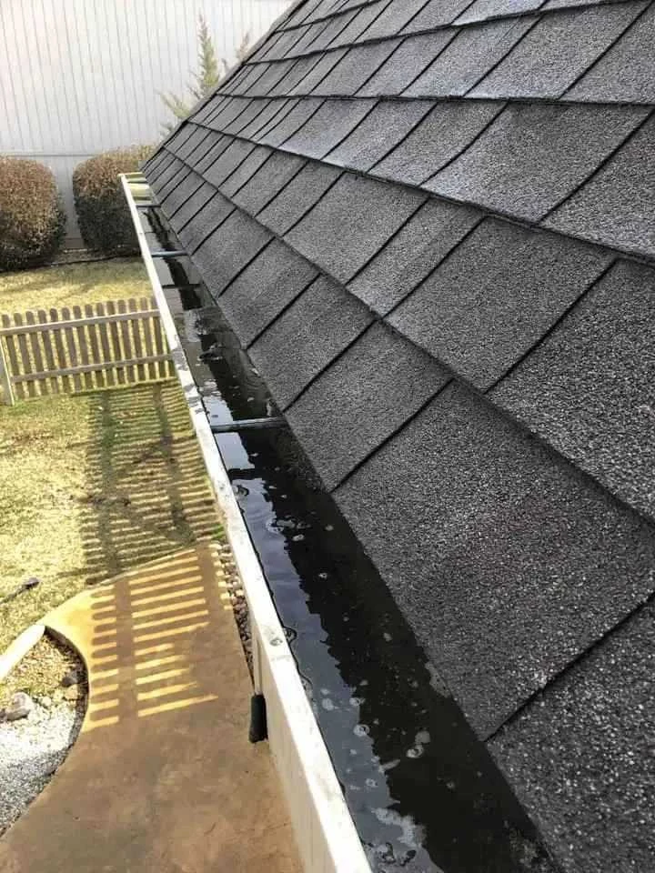 Residential rain gutter being cleared of leaves and debris